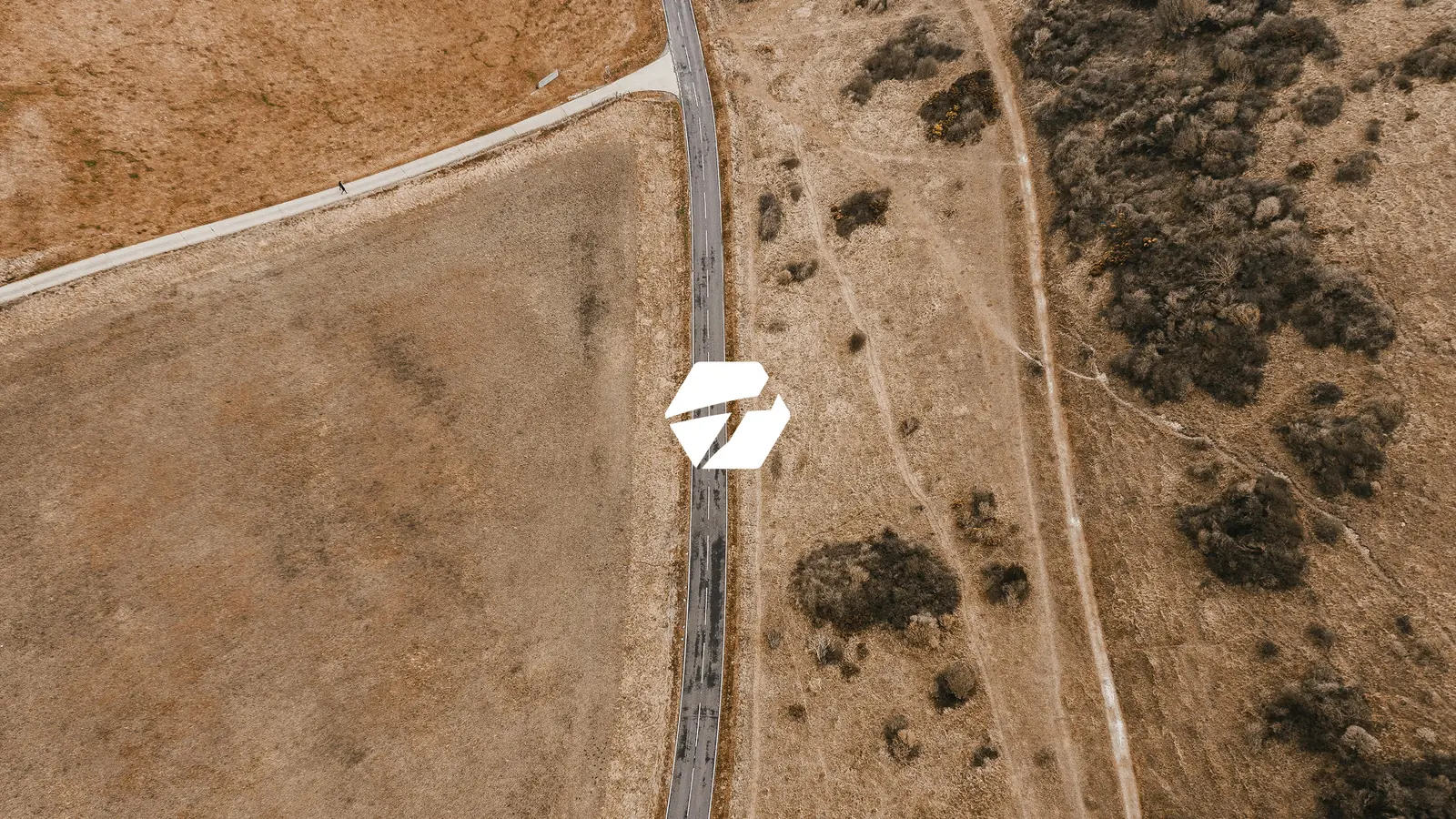 Taruh: símbolo de la marca sobre una fotografía aérea de un camino de tierra